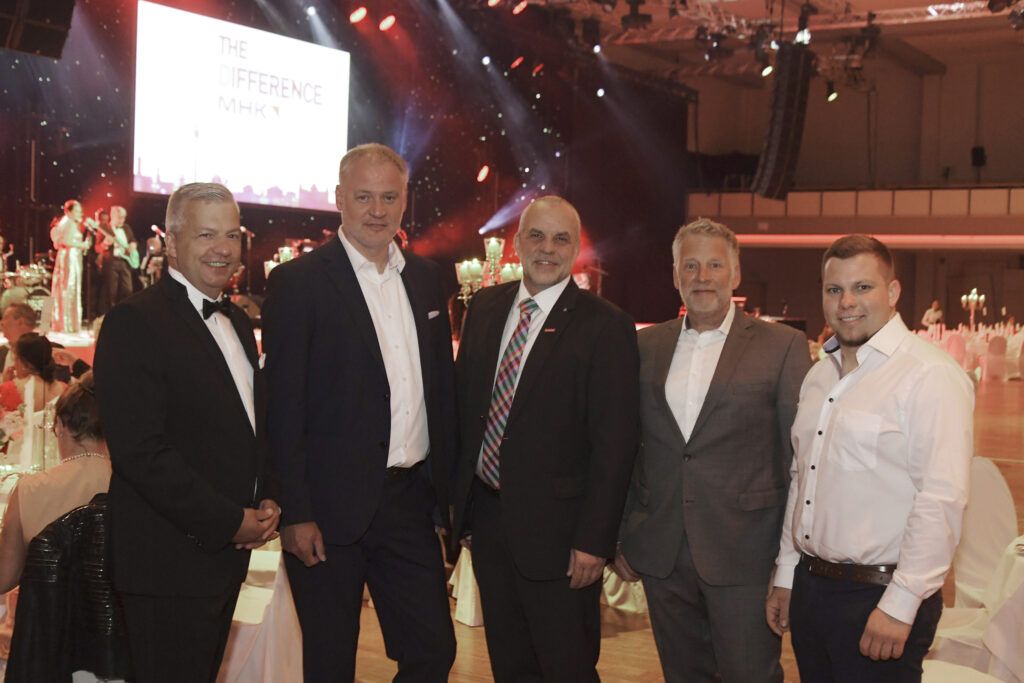 Fünf Männer, der neue Beirat von TOP-Malermeister-Deutschland, posieren in Anzügen in einem festlich beleuchteten Saal.